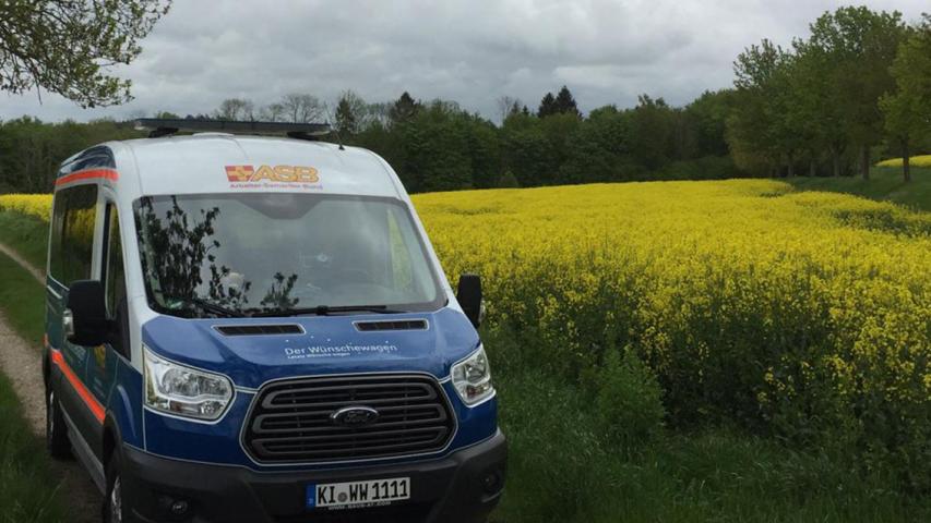 Symbolbild 1: Der ASB-Wünschewagen am blühenden Rapsfeld.